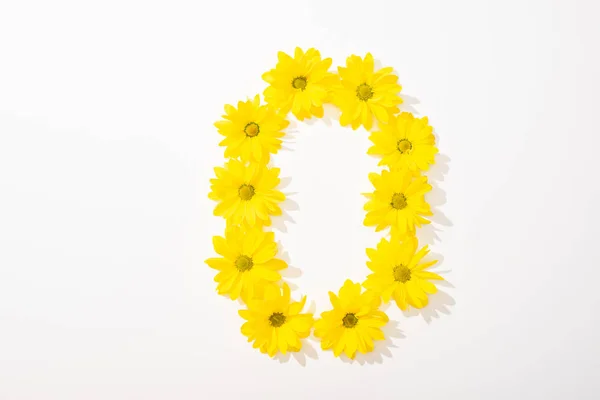 Vue du dessus des marguerites jaunes disposées en lettre O sur fond blanc — Photo de stock