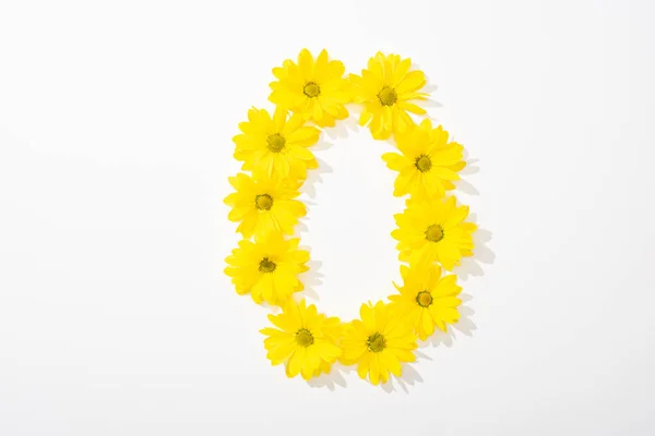 Top view of yellow daisies arranged in number 0 on white background — Stock Photo