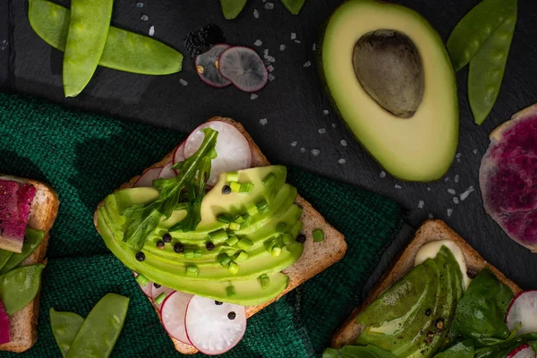 Top view of healthy sandwiches with radish, green peas and avocado on cloth — Stock Photo