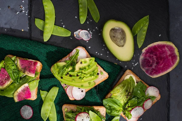 Vista superior de sanduíches vegetarianos saudáveis com legumes frescos em pano e placa de pedra — Fotografia de Stock