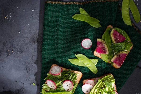 Vista superior de sándwiches vegetarianos con rábano y guisantes verdes sobre tela - foto de stock
