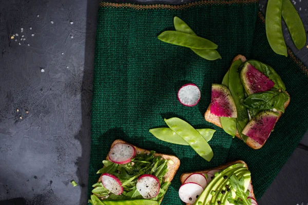 Vue de dessus des sandwichs végétariens avec radis et pois verts sur tissu — Photo de stock