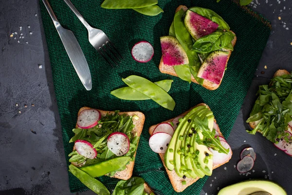 Vista superior de torradas vegetarianas saudáveis com legumes frescos em pano com garfo e faca — Fotografia de Stock