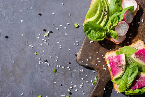 Top view of healthy sandwiches with vegetables on wooden board with pepper and salt — Stock Photo