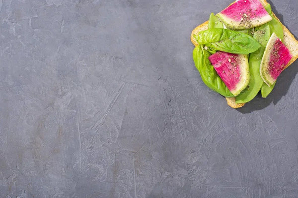 Vista superior de la tostada con guisantes verdes, albahaca y rábano en la mesa de piedra - foto de stock