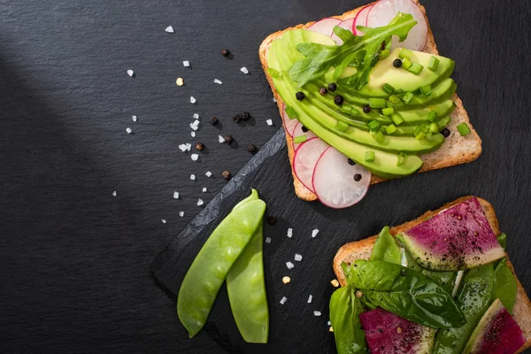 Vista dall'alto di panini freschi con verdure su tavola di pietra con pepe e sale — Foto stock