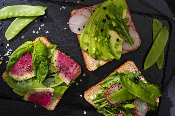 Vista superior de tostadas saludables con verduras crudas con semillas de pimienta y sal - foto de stock