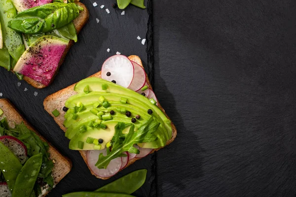 Top view of vegetarian sandwiches with vegetables on stone board with pepper and salt — Stock Photo