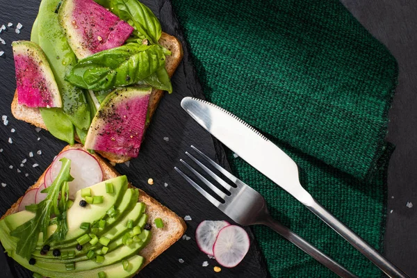 Vue de dessus des sandwichs sains avec des légumes frais sur tissu avec fourchette et couteau — Photo de stock