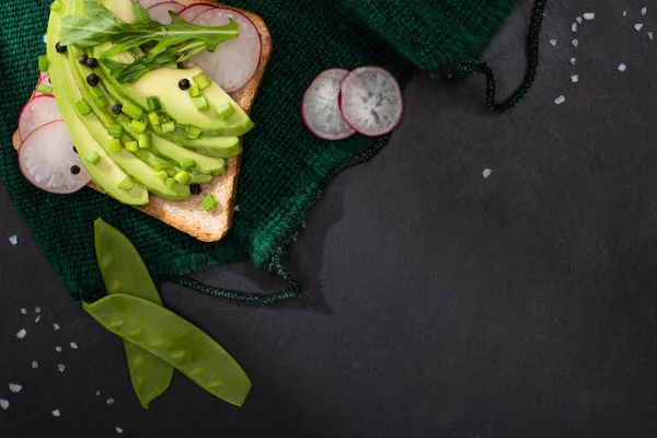 Vue du dessus du pain grillé avec avocat et poireau et radis sur tissu — Photo de stock