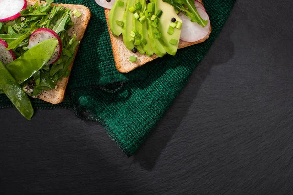 Vue de dessus des sandwichs végétariens au radis, poireau et avocat sur tissu vert — Photo de stock