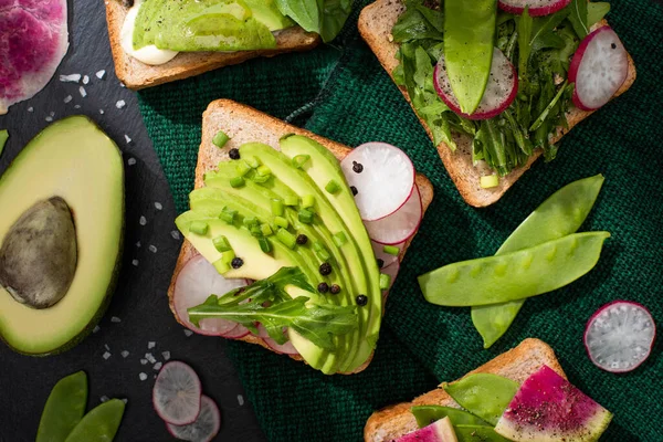 Vista superior de tostadas vegetarianas con verduras frescas paño verde - foto de stock