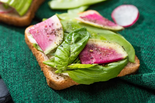 Nahaufnahme vegetarischer Sandwiches mit Rettich, Basilikum und Avocado auf Tuch — Stockfoto