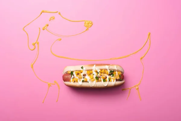 Top view of yummy hot dog with corn on pink with dog drawn with mustard — Stock Photo