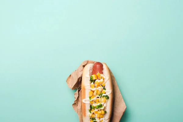 Vue du dessus de délicieux hot dog avec du maïs en papier sur bleu — Photo de stock