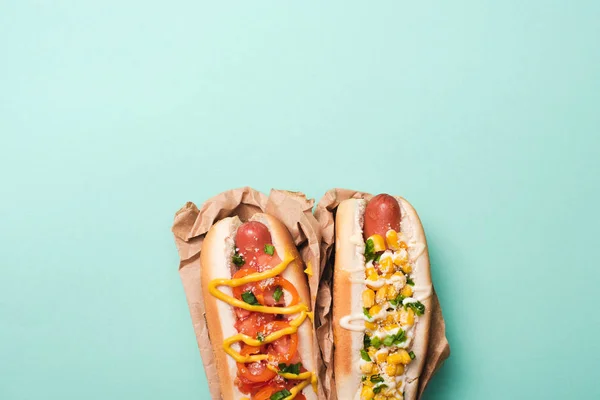 Vista superior de dos deliciosos hot dogs en papel sobre azul - foto de stock