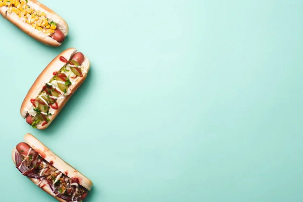 Vue de dessus de trois hot-dogs malsains sur bleu — Photo de stock