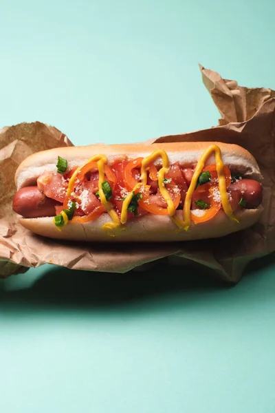 Draufsicht auf leckeren Hot Dog in Papier auf Blau — Stockfoto