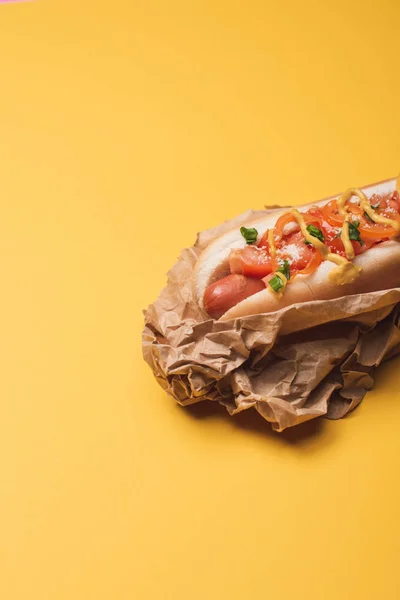 Un delicioso hot dog americano en papel sobre amarillo - foto de stock