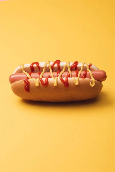 Sabroso perro caliente americano con salchicha, mostaza y ketchup en amarillo - foto de stock