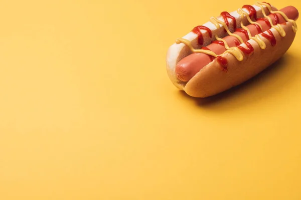 Delicioso perrito caliente con salchicha, mostaza y ketchup en amarillo - foto de stock
