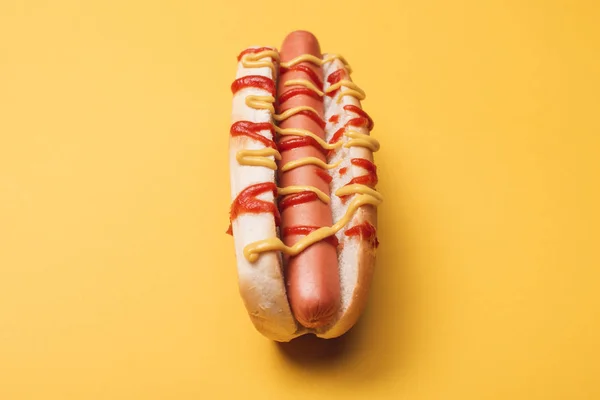 Délicieux hot-dog malsain avec saucisse, moutarde et ketchup sur jaune — Photo de stock