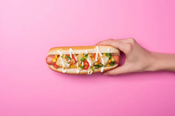 Vista cortada de mulher segurando saboroso cachorro-quente em rosa — Fotografia de Stock