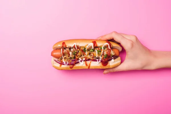 Visão parcial da mulher segurando um cachorro-quente saboroso em rosa — Fotografia de Stock