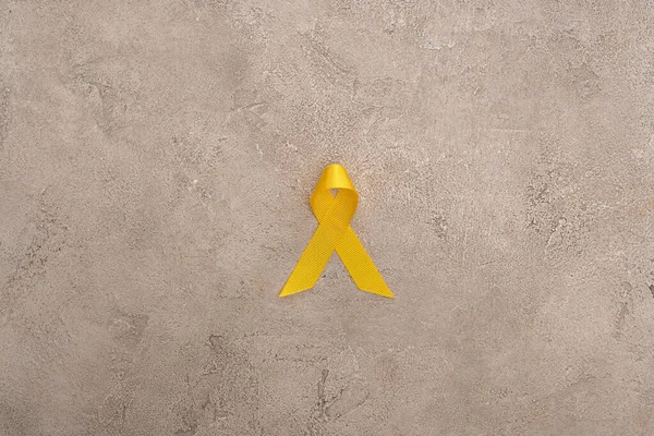 Вид зверху на жовту стрічку на сірому фоні, концепція міжнародного дня дитячого раку — Stock Photo