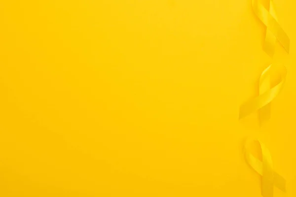 Vue du dessus des rubans jaunes sur fond lumineux et coloré, concept de journée internationale contre le cancer chez les enfants — Photo de stock