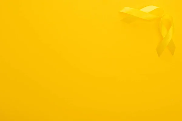 Top view of yellow awareness ribbons on bright colorful background, international childhood cancer day concept — Stock Photo