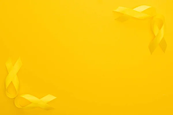 Вид зверху на стрічки поінформованості про жовтий на барвистому фоні, концепція міжнародного дня дитячого раку — стокове фото