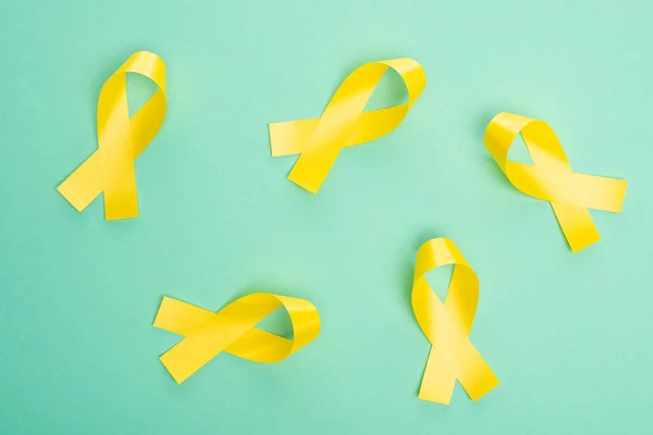 Vue du dessus des rubans jaunes sur fond turquoise, concept de journée internationale contre le cancer chez les enfants — Photo de stock