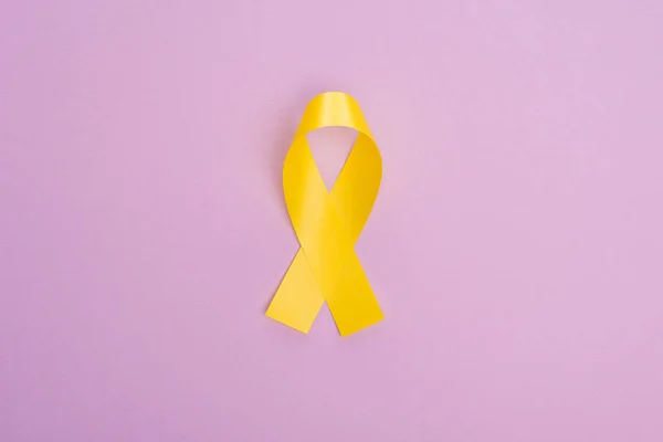 Vue du dessus du ruban jaune sur fond violet, concept de journée internationale contre le cancer chez les enfants — Photo de stock