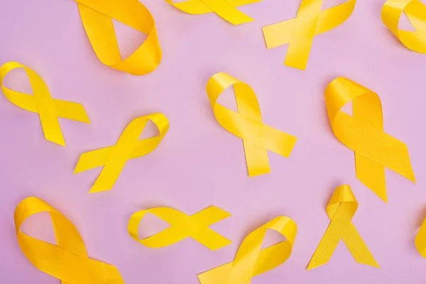 Top view of yellow ribbons on violet background, international childhood cancer day concept — Stock Photo