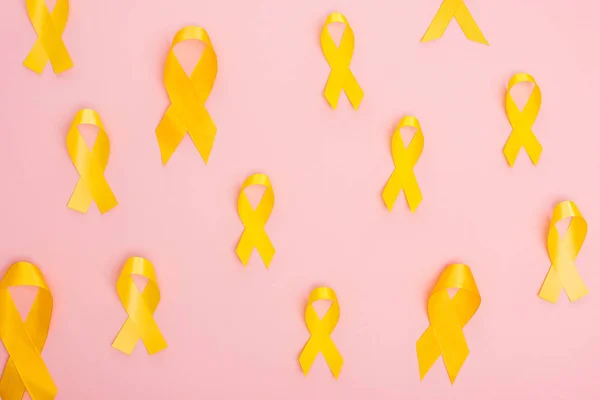 Top view of yellow ribbons on pink background, international childhood cancer day concept — Stock Photo