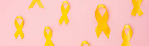 Vista superior de fitas amarelas em fundo rosa, tiro panorâmico, conceito de dia internacional do câncer infantil — Fotografia de Stock