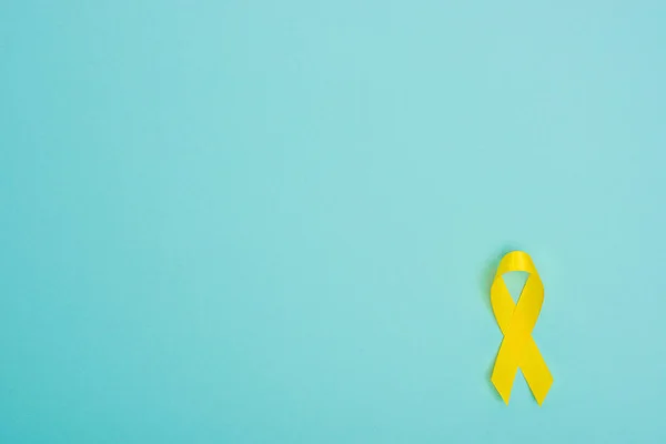 Vista superior de la cinta amarilla sobre fondo azul, concepto del día internacional del cáncer infantil - foto de stock