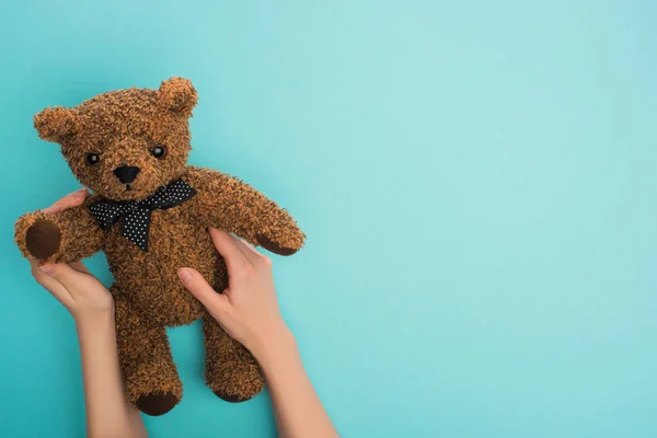 Vista recortada de la mujer sosteniendo oso de peluche sobre fondo azul - foto de stock