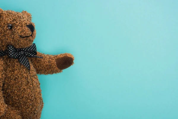 Vista superior del osito de peluche marrón con lazo sobre fondo azul - foto de stock