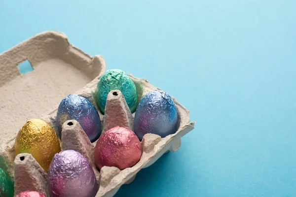 Chocolate easter eggs in egg tray on blue background — Stock Photo