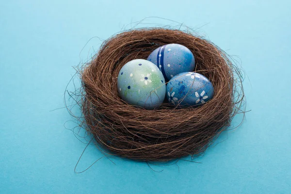 Vue rapprochée des œufs de Pâques dans le nid sur bleu — Photo de stock