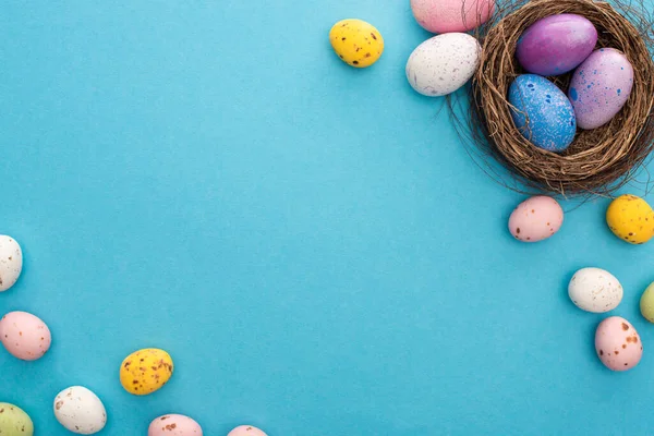 Top view of colorful chicken and quail eggs with nest on blue background — Stock Photo