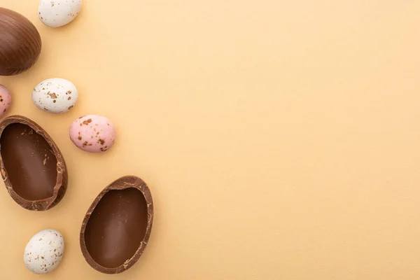 Draufsicht auf bunte Wachteln und Schokoladeneier auf beigem Hintergrund — Stockfoto