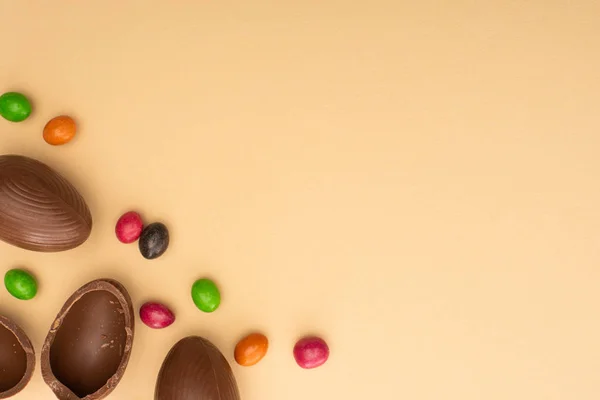 Top view of chocolate eggs and sweets on beige background — Stock Photo