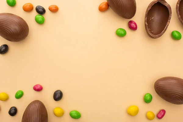 Вид зверху на шоколадні яйця та смачні цукерки на бежевому фоні — стокове фото