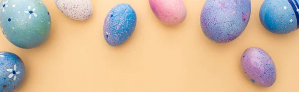 Vista dall'alto di uova di Pasqua viola su sfondo beige, scatto panoramico — Foto stock