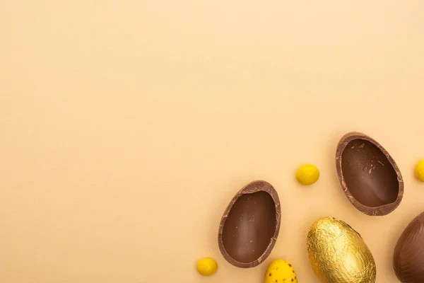 Vue du dessus des œufs de caille et de chocolat avec des bonbons jaunes sur fond beige — Photo de stock