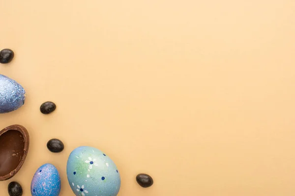 Верхний вид шоколада, перепела и куриных яиц с конфетами на бежевом фоне — стоковое фото