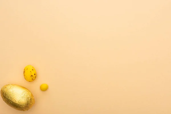 Vista dall'alto di caramelle, quaglie e uova di cioccolato su sfondo beige — Foto stock